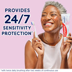 A woman smiling holding a toothbrush and a tube of Colgate Sensitive Maximum Strength Whitening Toothpaste. In text: Provides 24/7 sensitivity protection*. *With twice daily brushing after two weeks of continuous use.