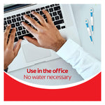 A man typing on a laptop next to two Colgate Max Fresh Wisp Disposable Mini Travel Toothbrushes. In text: Use in the office. No water necessary.