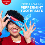A woman smiling while holding a tube of Colgate Max Fresh Toothpaste with Mini Breath Strips. In text: Invigorating peppermint toothpaste.
